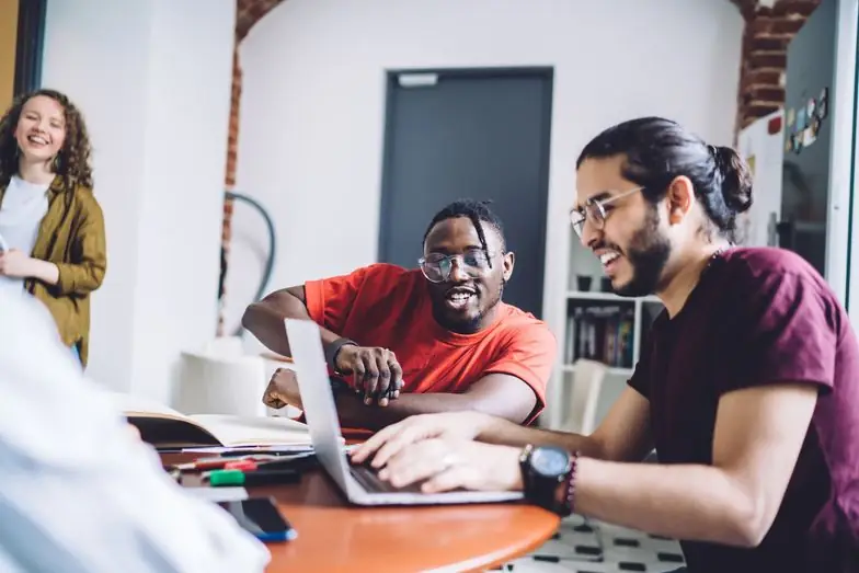 Two smiling colleagues working together at a laptop