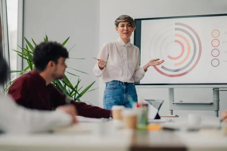 A woman presenting confidently at a whiteboard in a meeting room