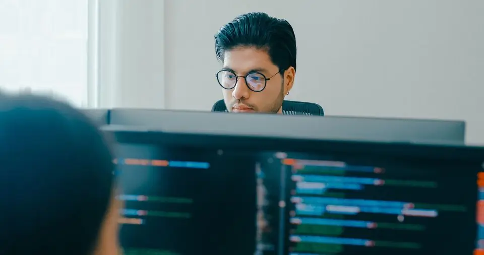 A man in glasses focused on his monitor at work