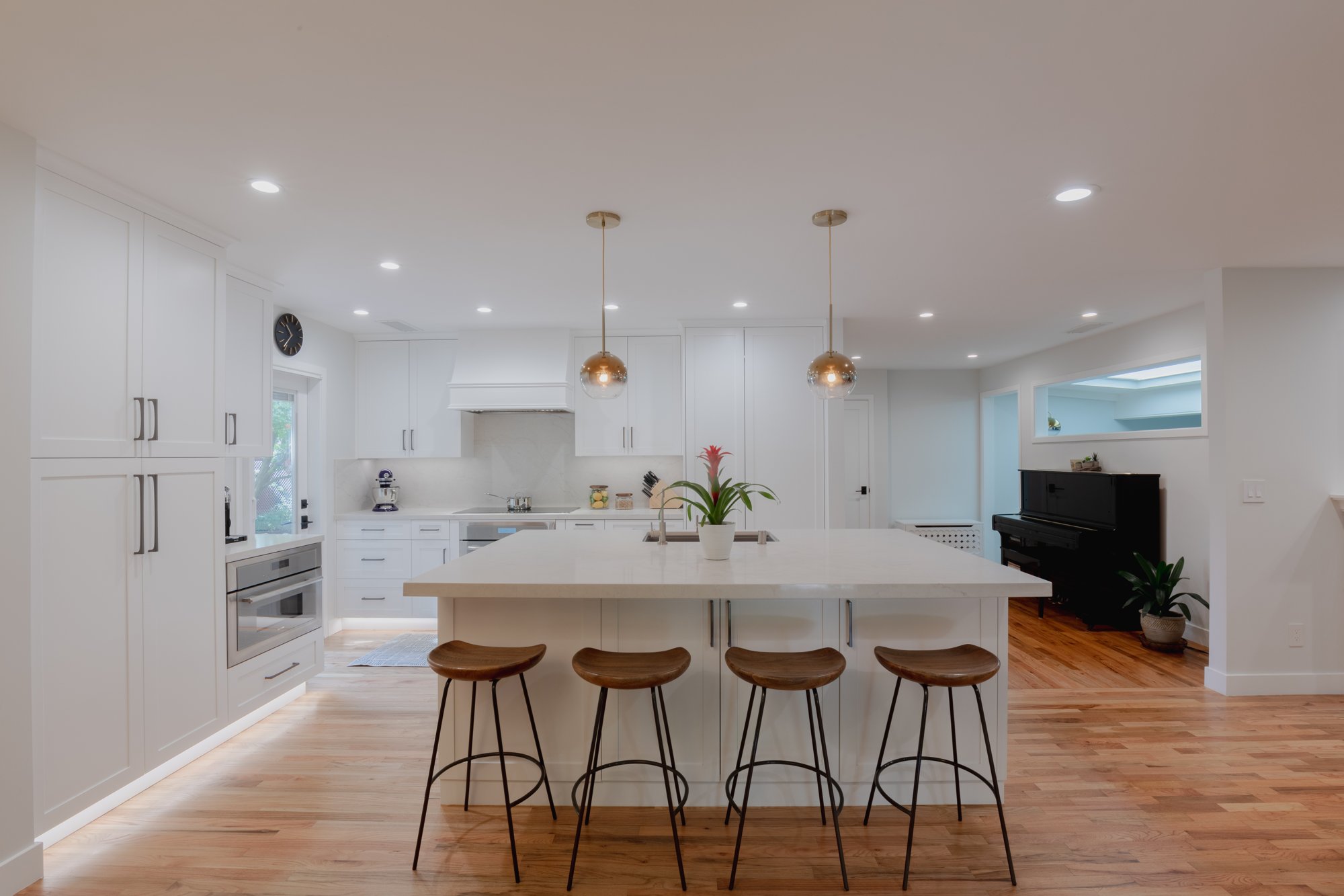 A bright kitchen with a pale island, warm pendant lights and garden-facing doors.