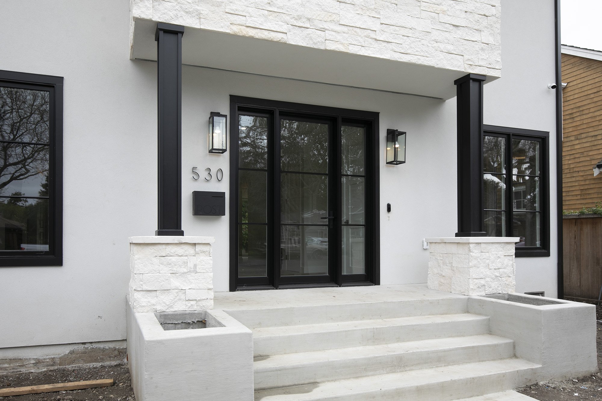 Front porch with white steps, dark double doors and a wall-mounted lantern.