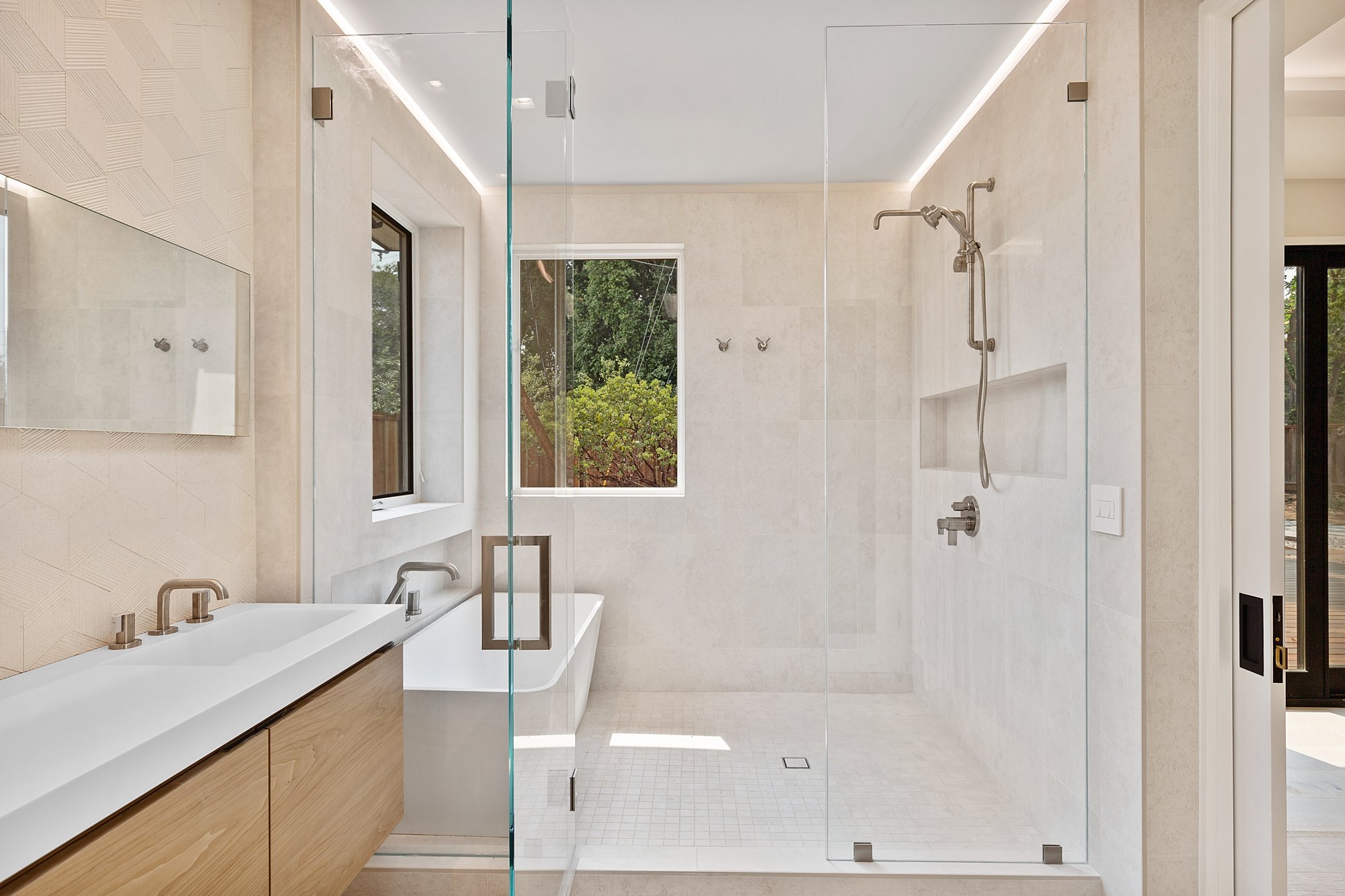 Bathroom with a long double vanity, glass shower and garden window.