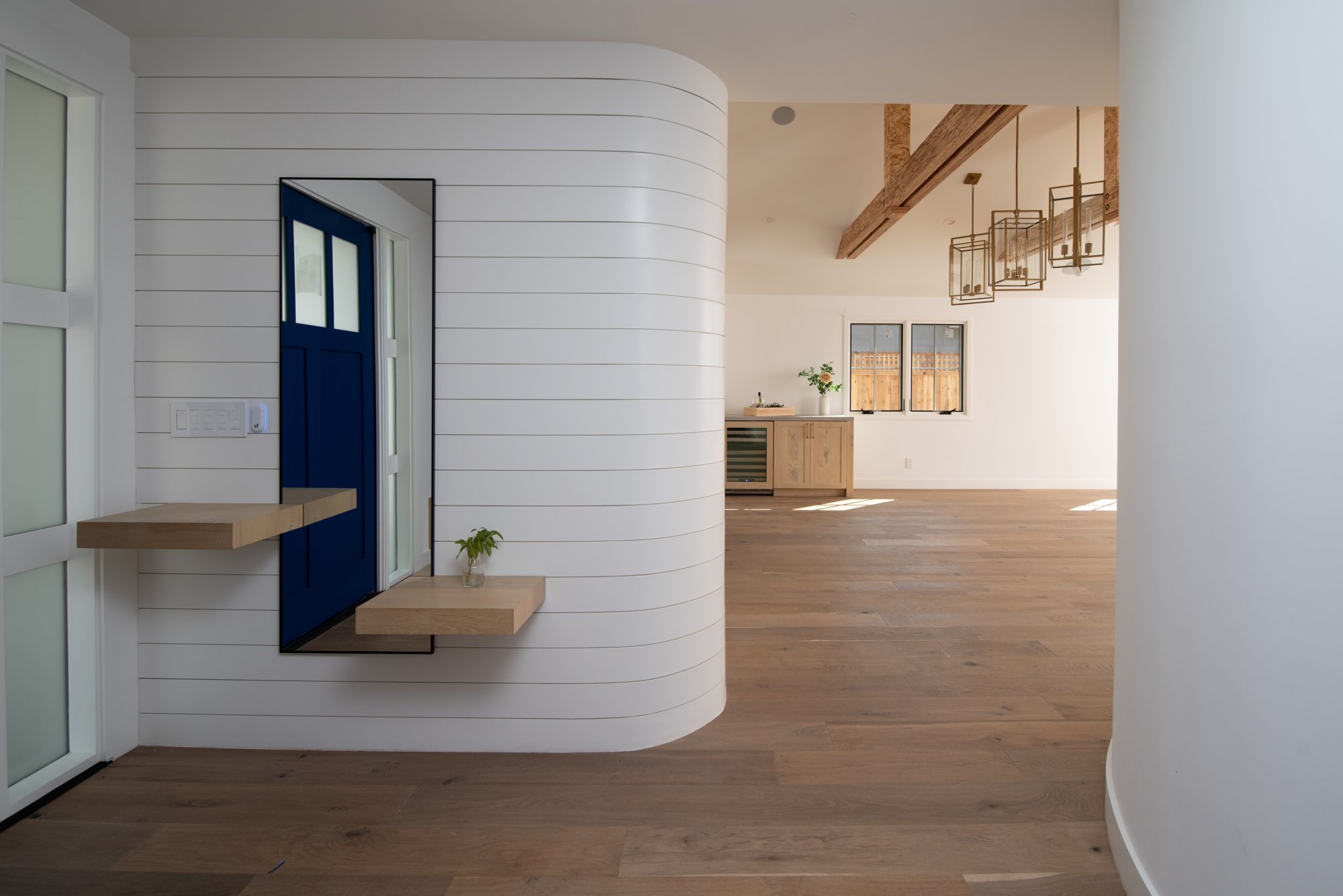 Entrance hall with blue front door, pale wood floor and exposed timber beams.