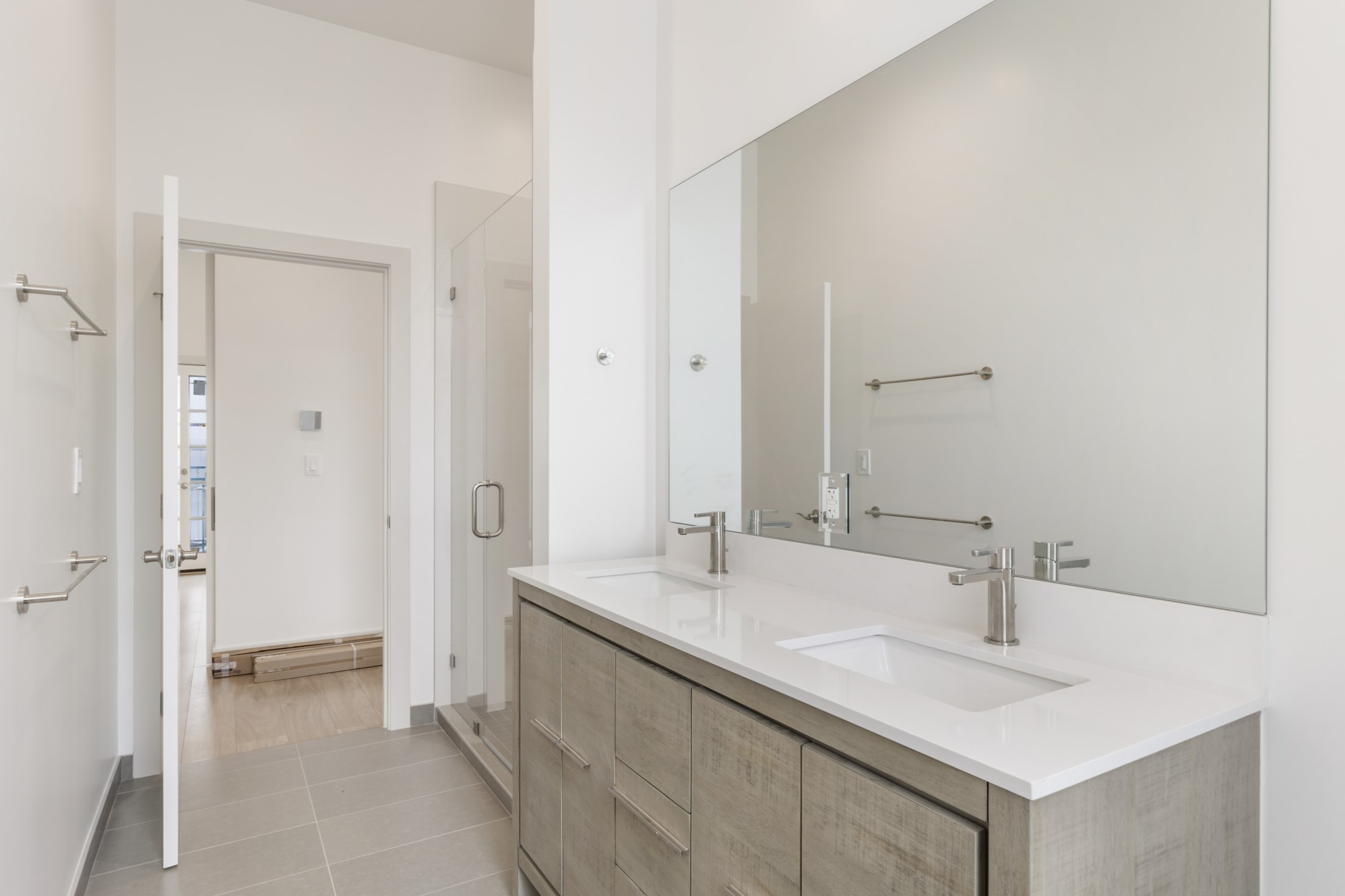 Bathroom with pale wood vanity, twin basins and a broad wall mirror.