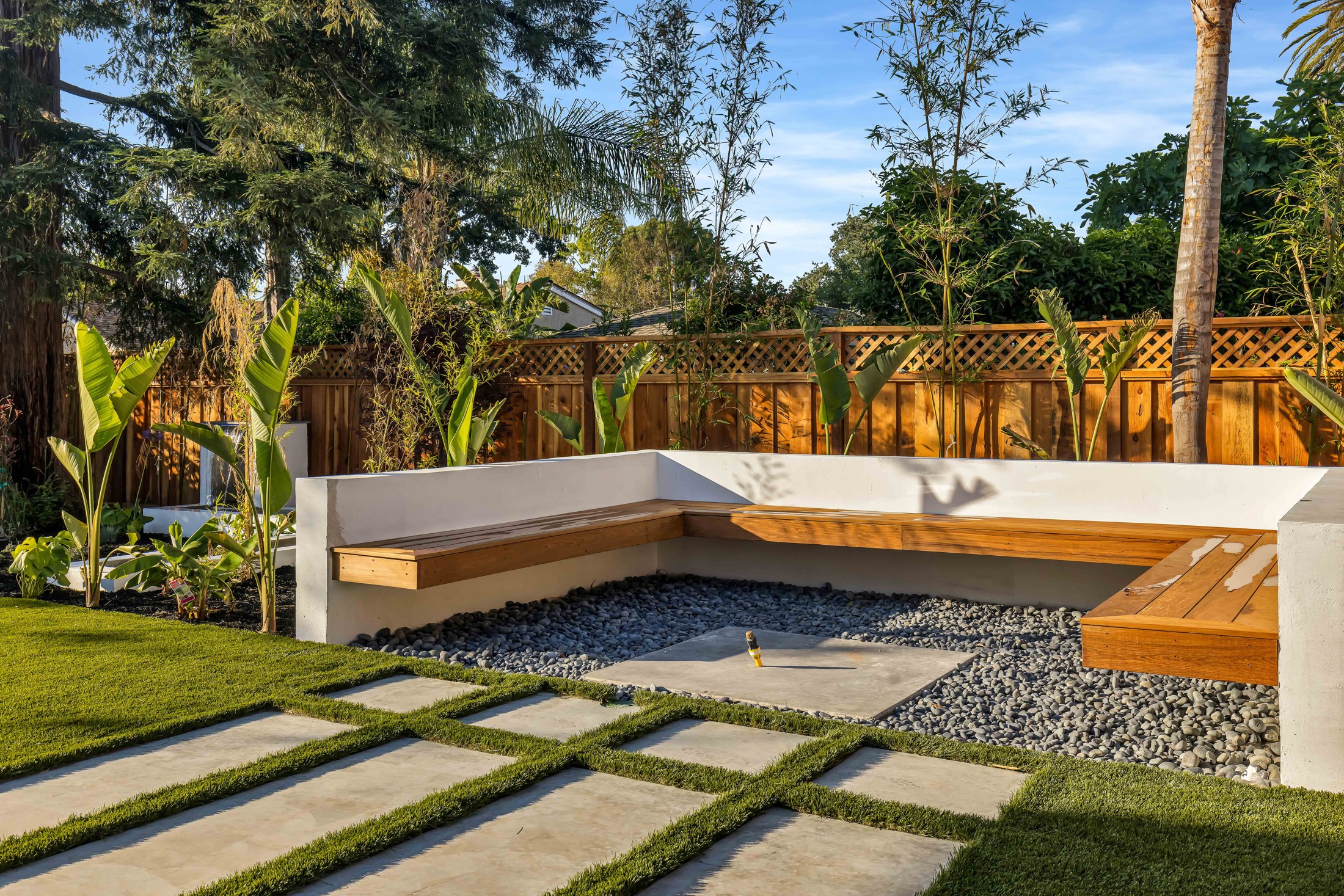 Sunken garden seating area with timber benches, stepping stones and established planting.