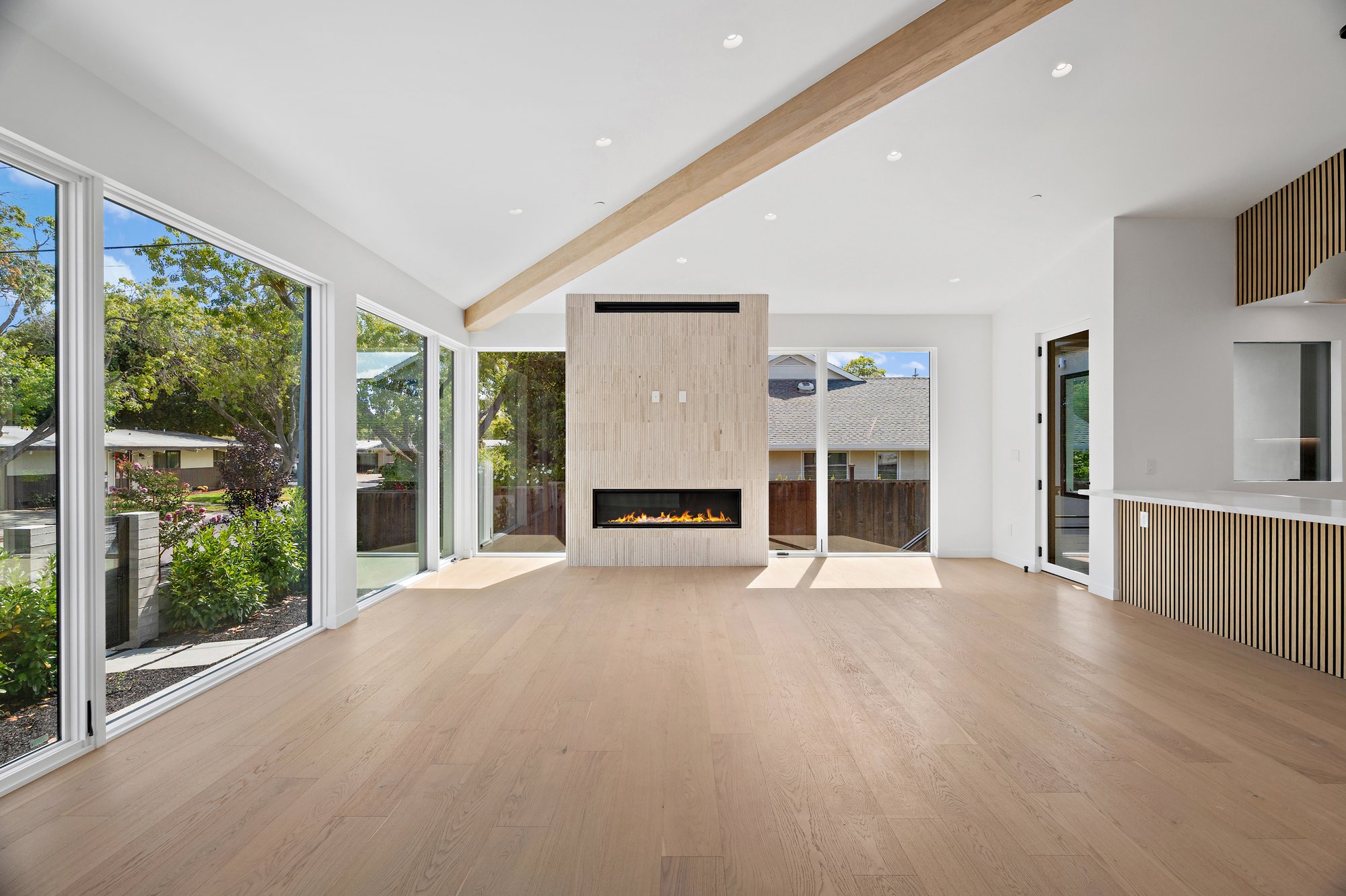 Contemporary living area beneath a broad ceiling plane with garden-facing glazing.