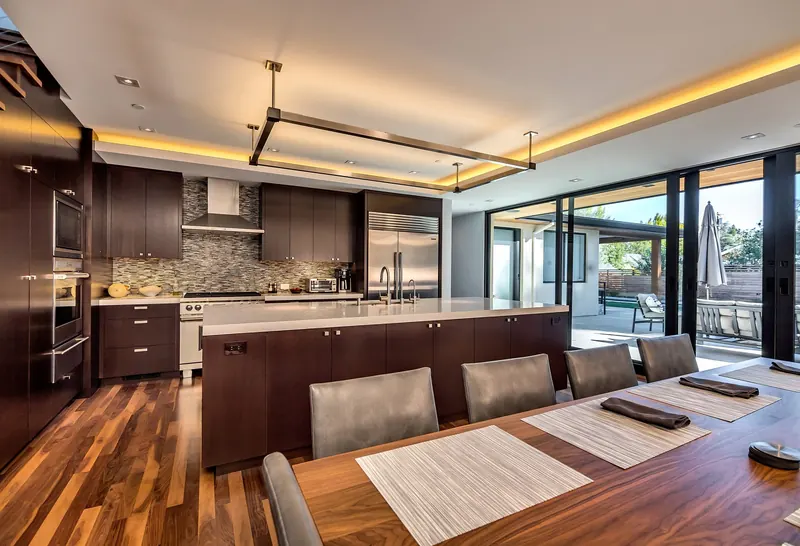 Contemporary kitchen with dark wood cabinetry, a broad island, and large garden-facing glass doors.