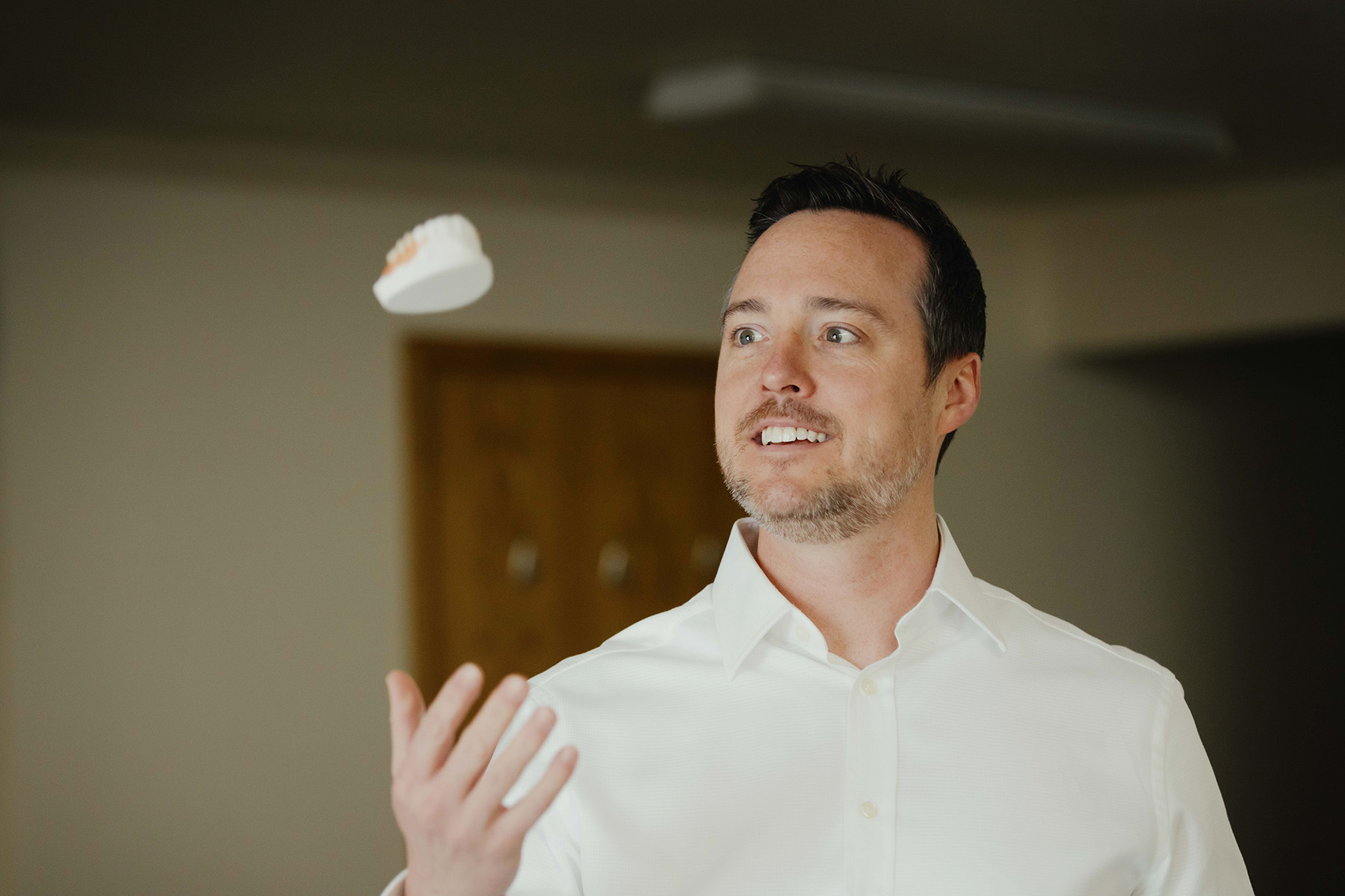 Dr. Pearson smiling, throwing a set of dentures in the air