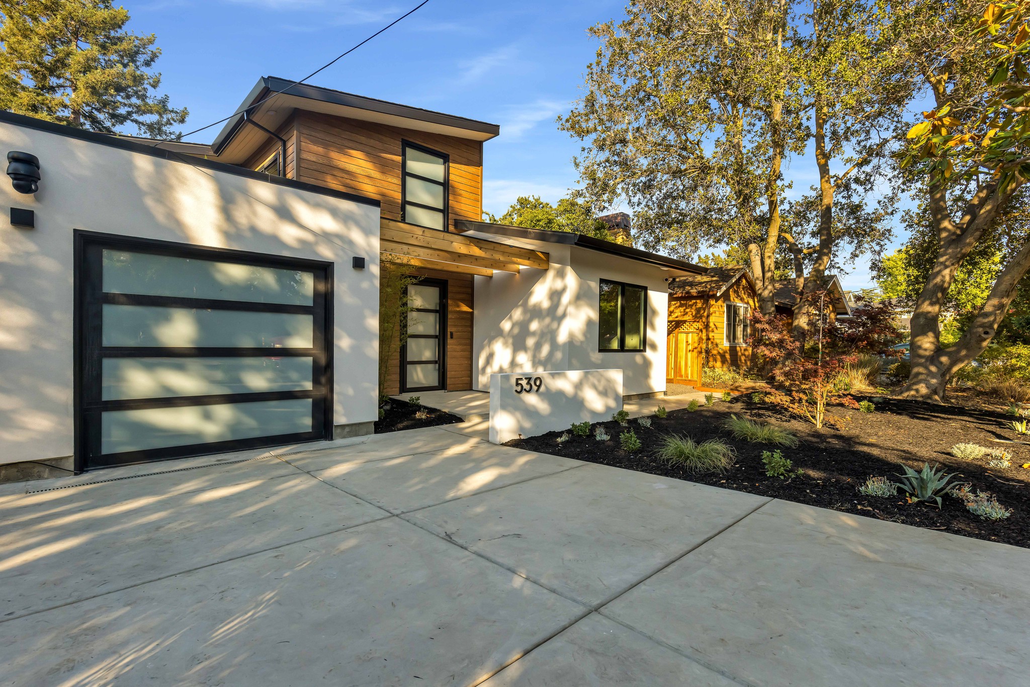 Two-story house with glass-panel garage door and concrete driveway.