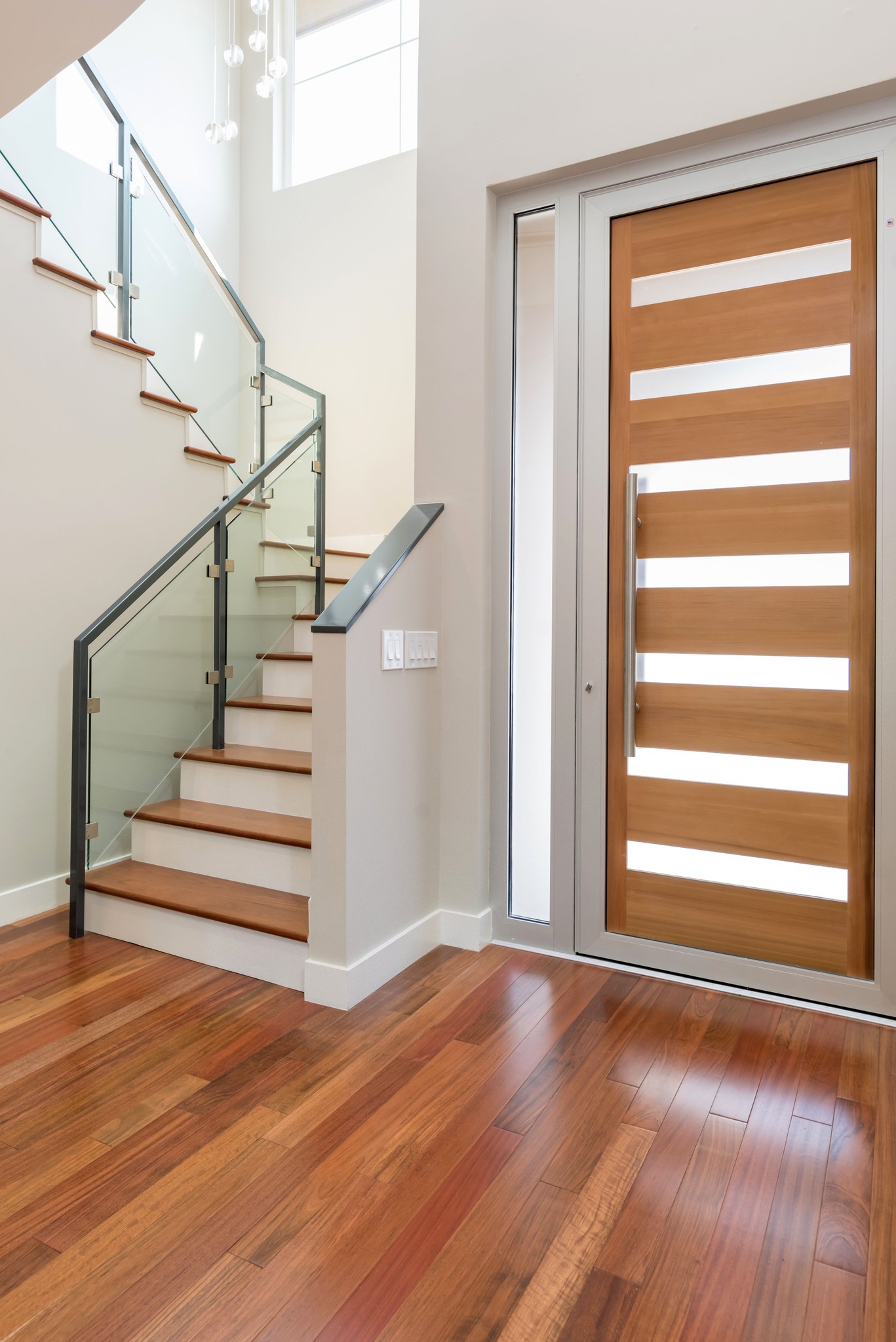 Wood front door and staircase with a glass railing.