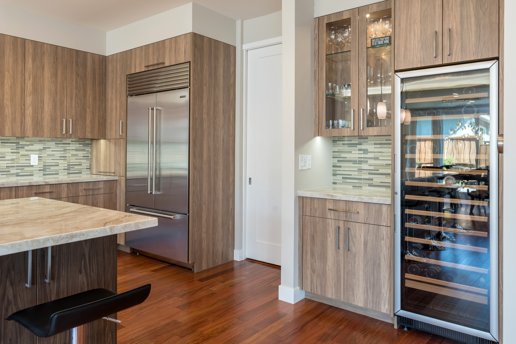 Wood kitchen cabinetry with a built-in refrigerator and glass-front wine cooler.