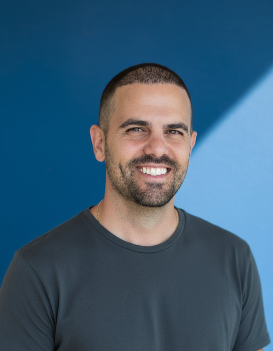 Portrait of Maor Greenberg against a blue background.