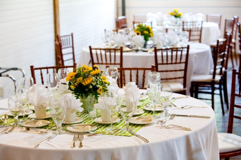 Round reception tables set with white linens and yellow flower centerpieces