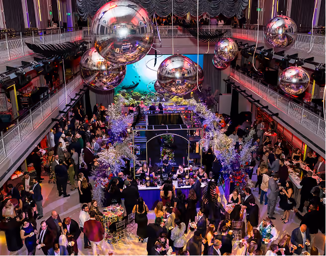 Guests at a corporate gala in a grand hall decorated with mirror balls