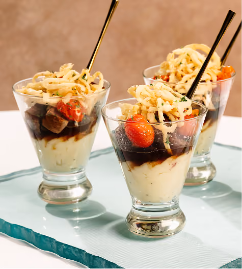 Short ribs over mashed potatoes with cherry tomatoes and crispy onions, served in glasses