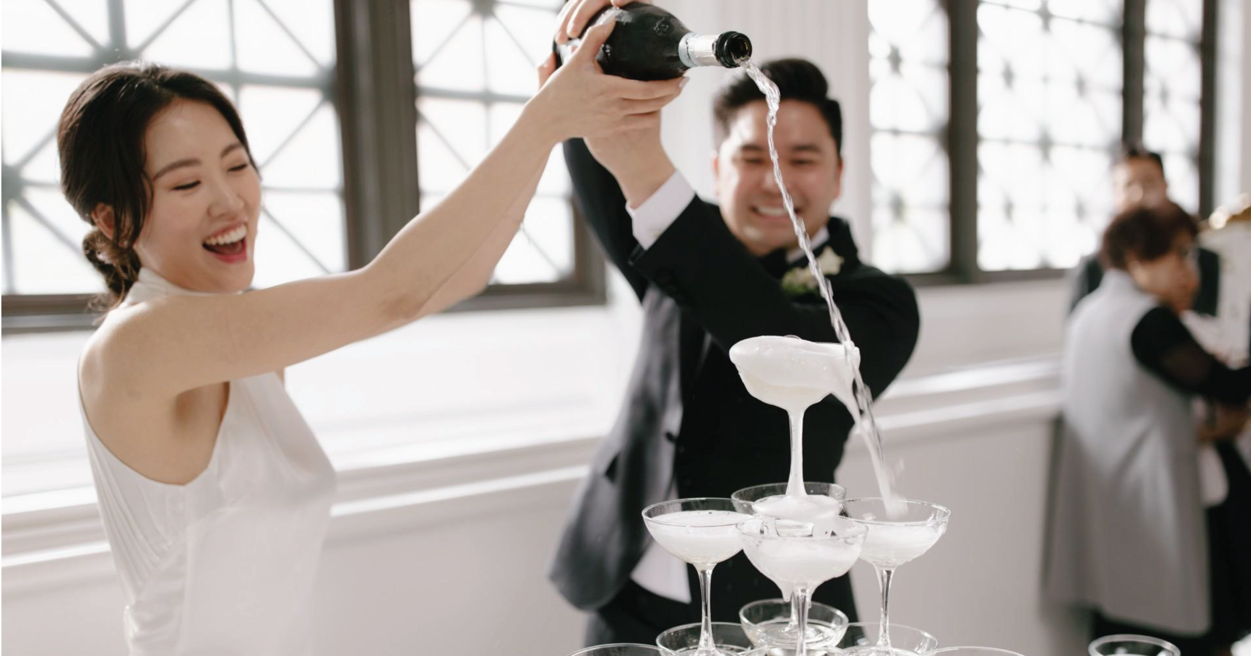 Bride and groom pouring champagne over a champagne tower at their reception