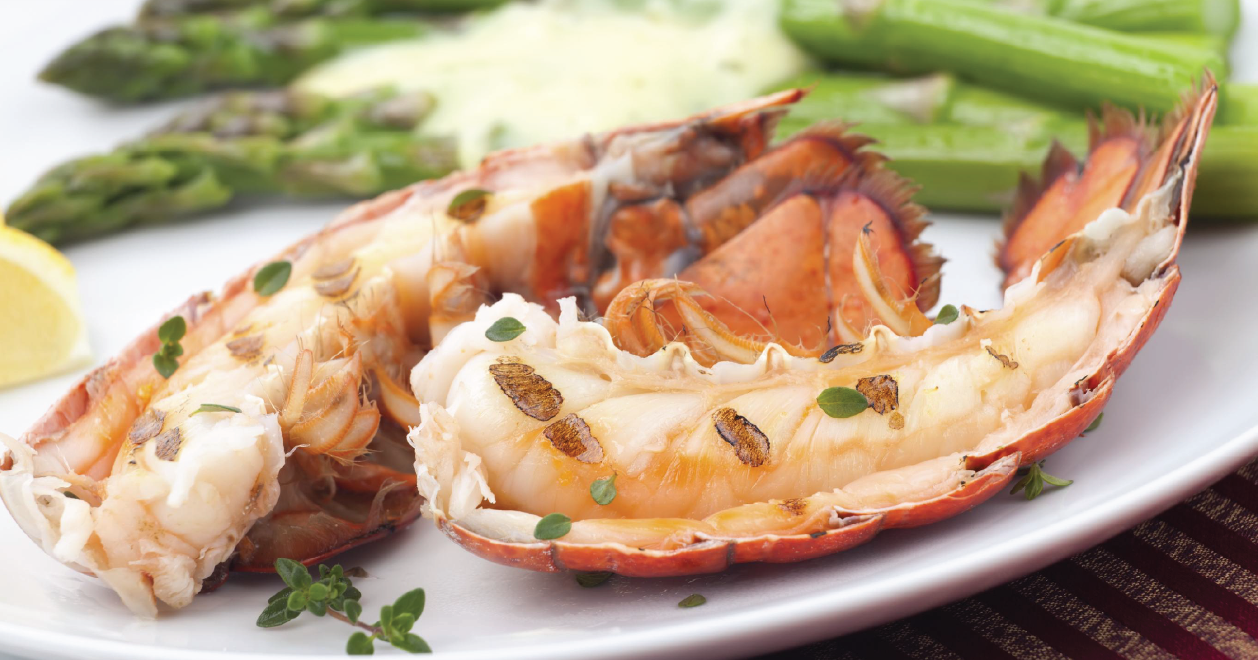 Grilled lobster tails served with asparagus and lemon