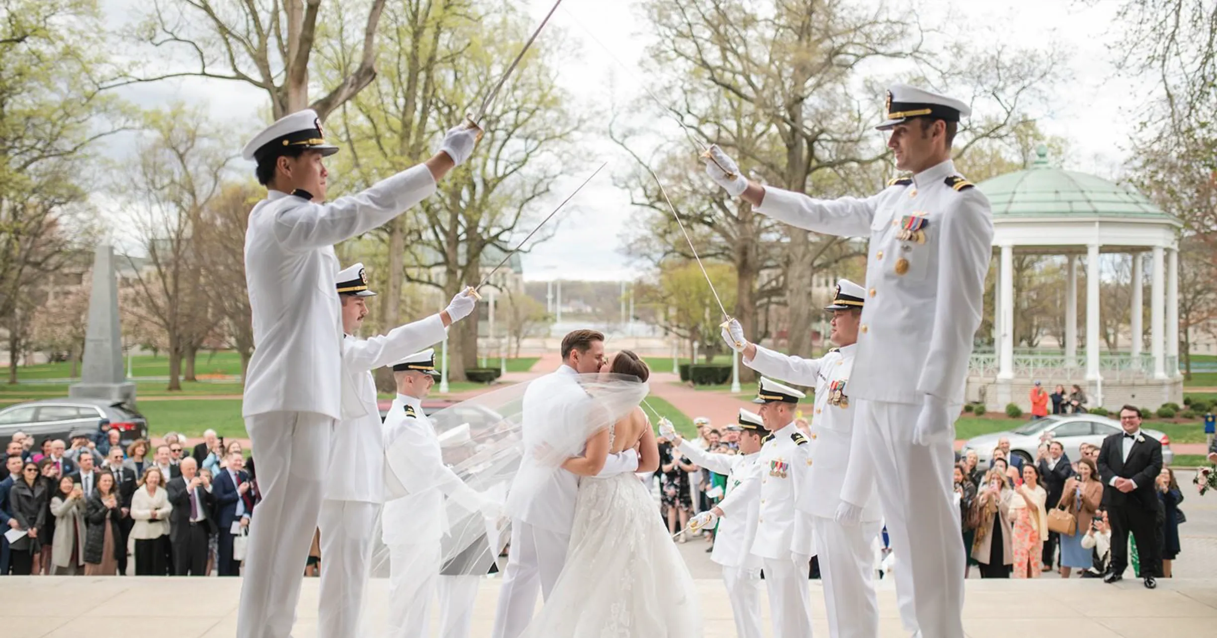 Bride and groom celebrating with Navy officers in dress whites at an outdoor wedding
