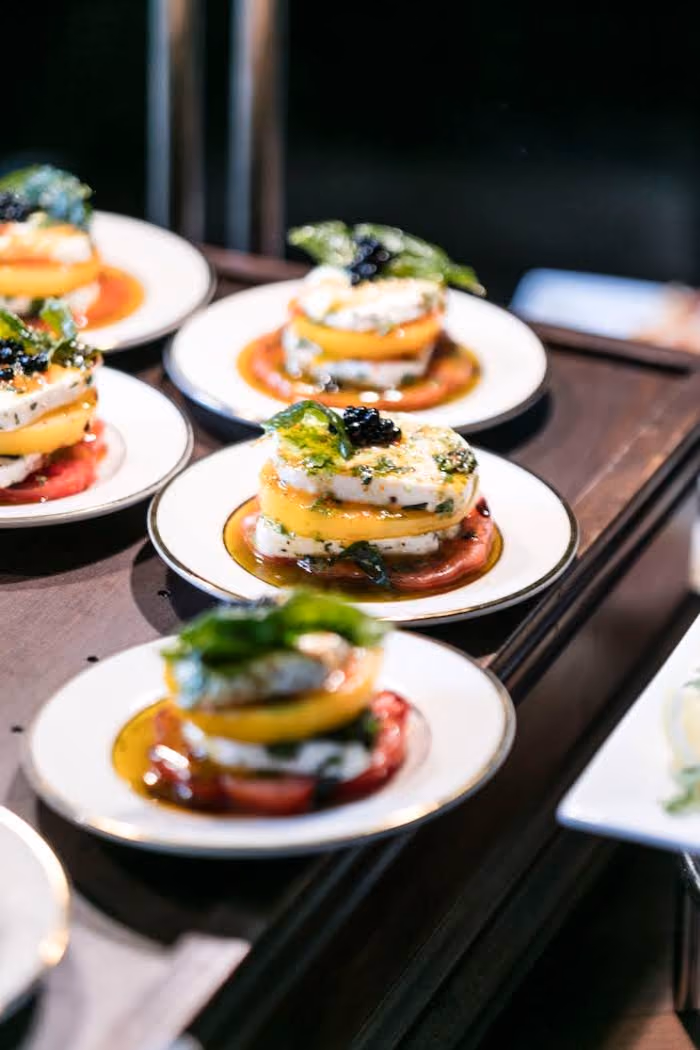 Stacked caprese salads with heirloom tomatoes, mozzarella and basil on small plates