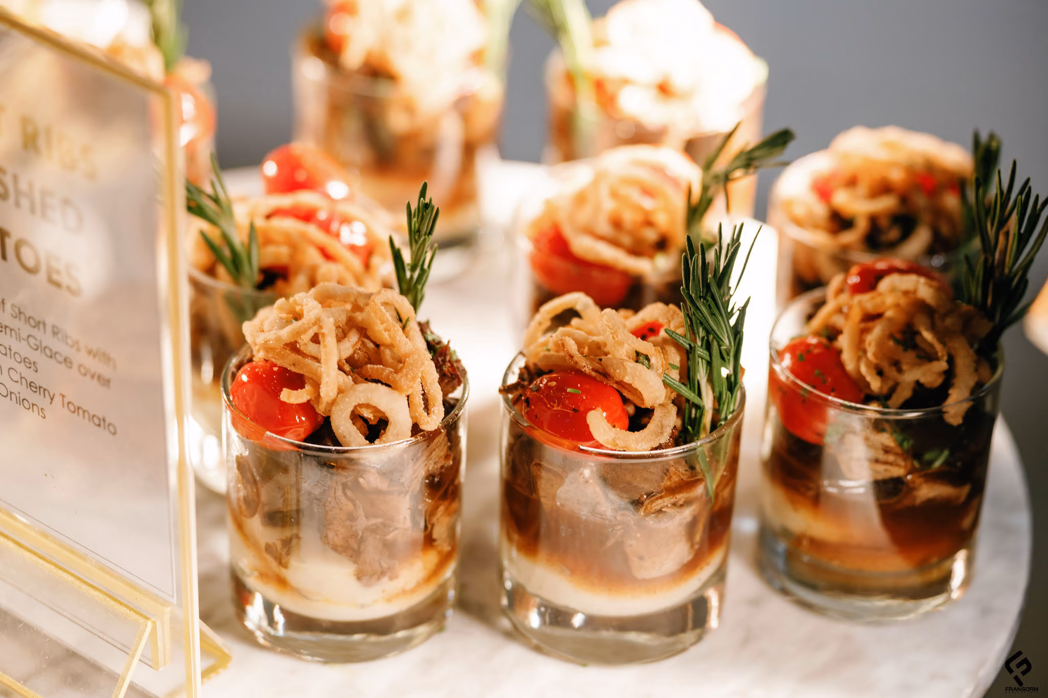 Short rib and mashed potato appetizer glasses topped with crispy onions, cherry tomato and rosemary
