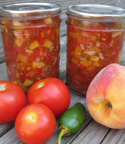 Jars of peach salsa with fresh tomatoes and a Georgia peach