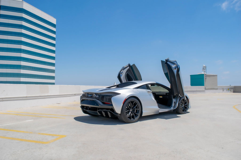 Rear view of a silver McLaren Artura with its doors raised.