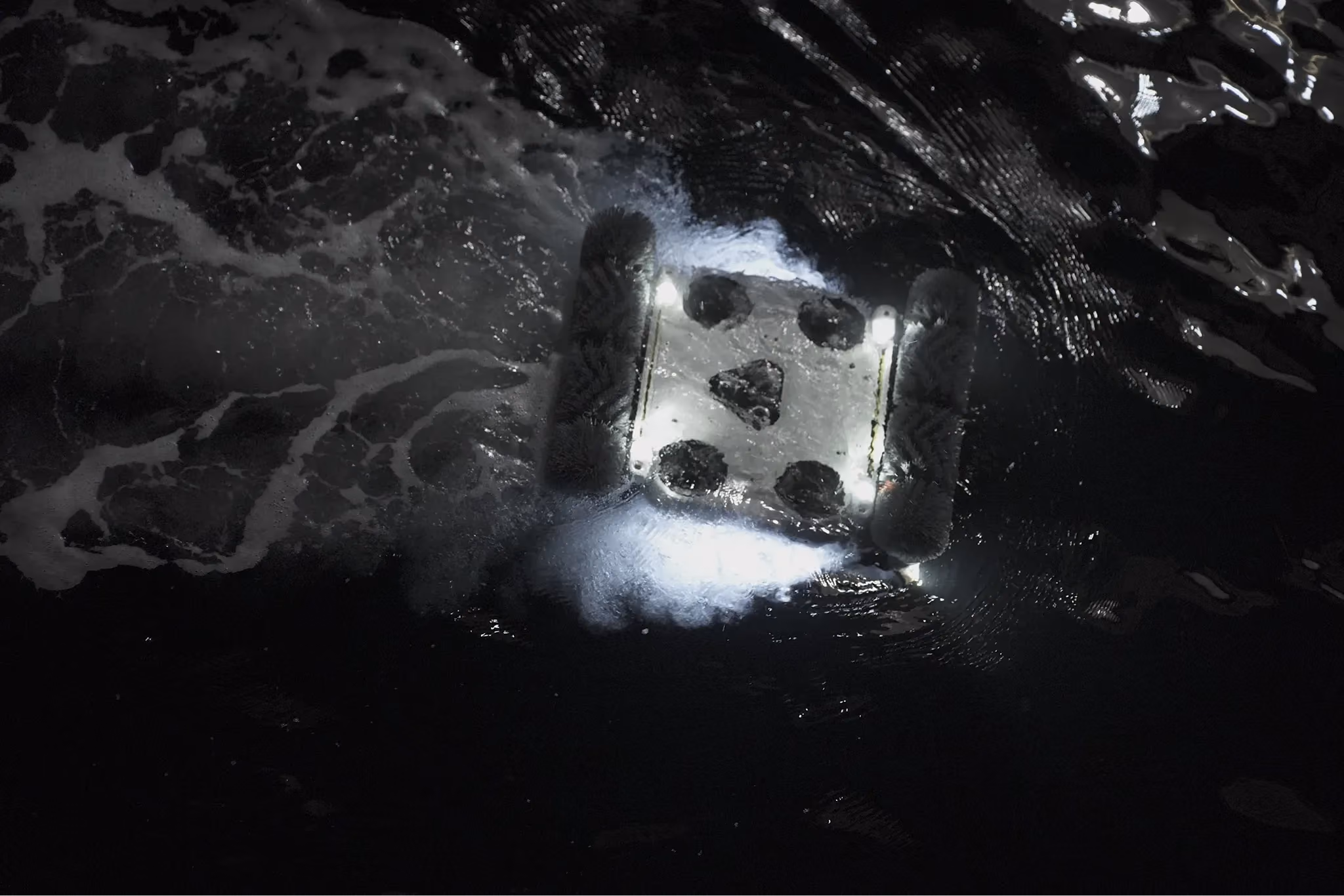 Hullbot robot working at night, its lights illuminating the dark water around it