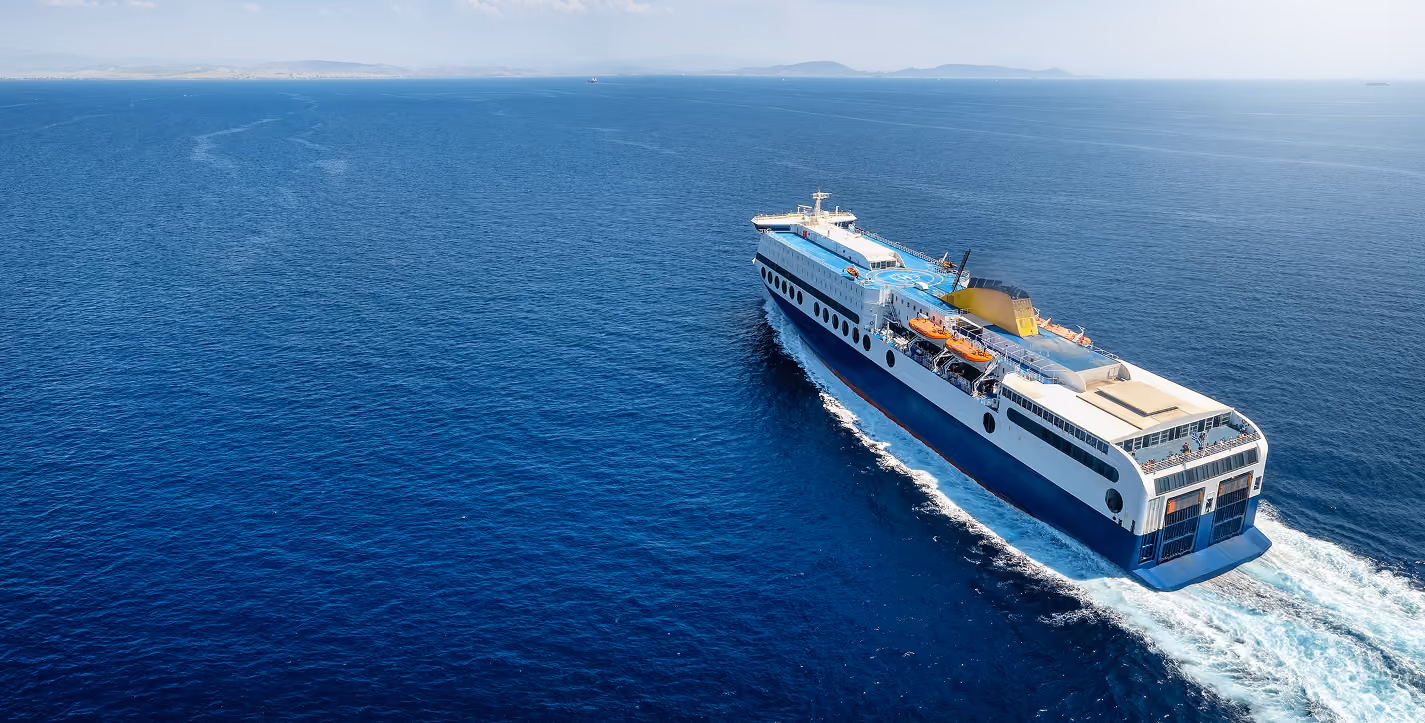 Container ship fully loaded with containers sailing across calm open sea under a blue sky
