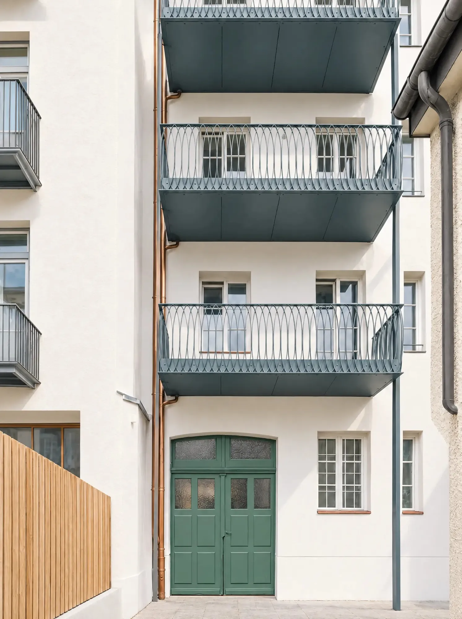 Hoffassade mit neuen Stahlbalkonen und grüner Holztür