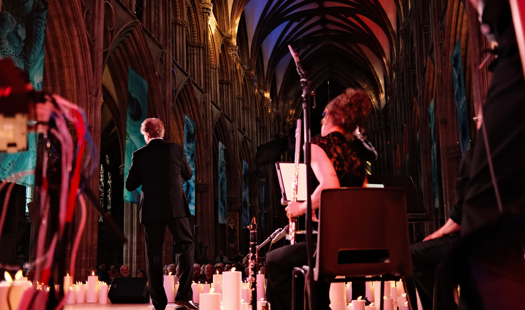 A Valjean singing to the audience beside the live band in a candlelit cathedral