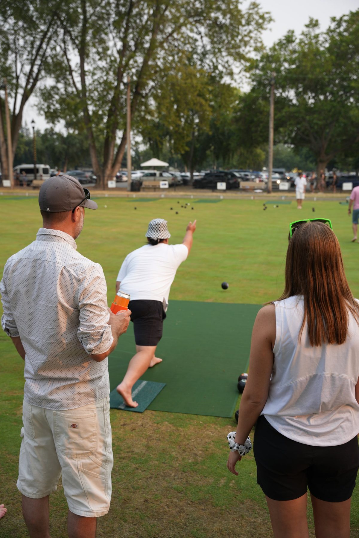 A CTC staff member bowls while two colleagues watch