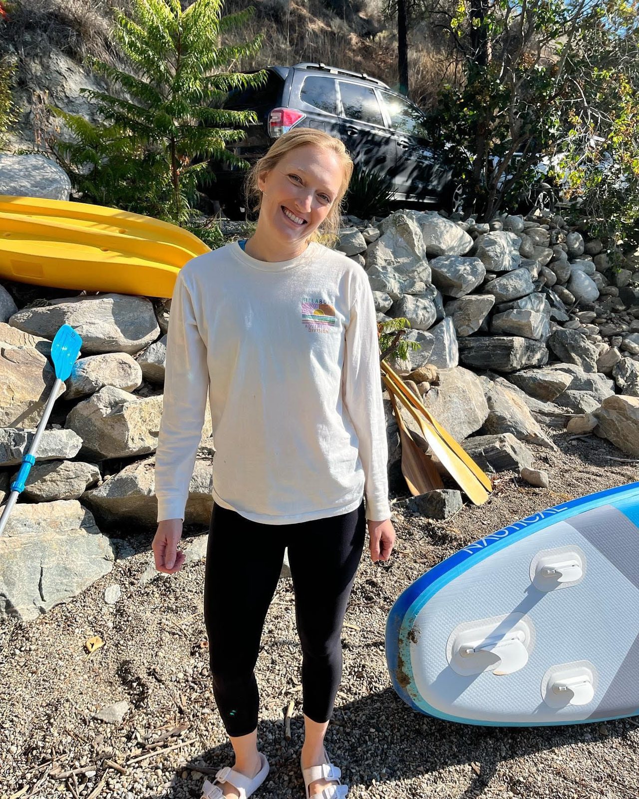Kelly, a CTC team member, by an Okanagan lake with kayaks and paddleboards