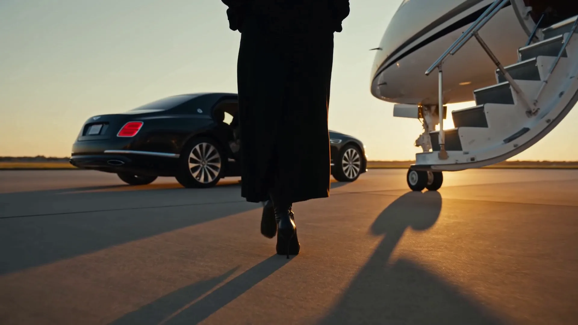 A woman walks to a private jet at sunset, a black sedan waiting