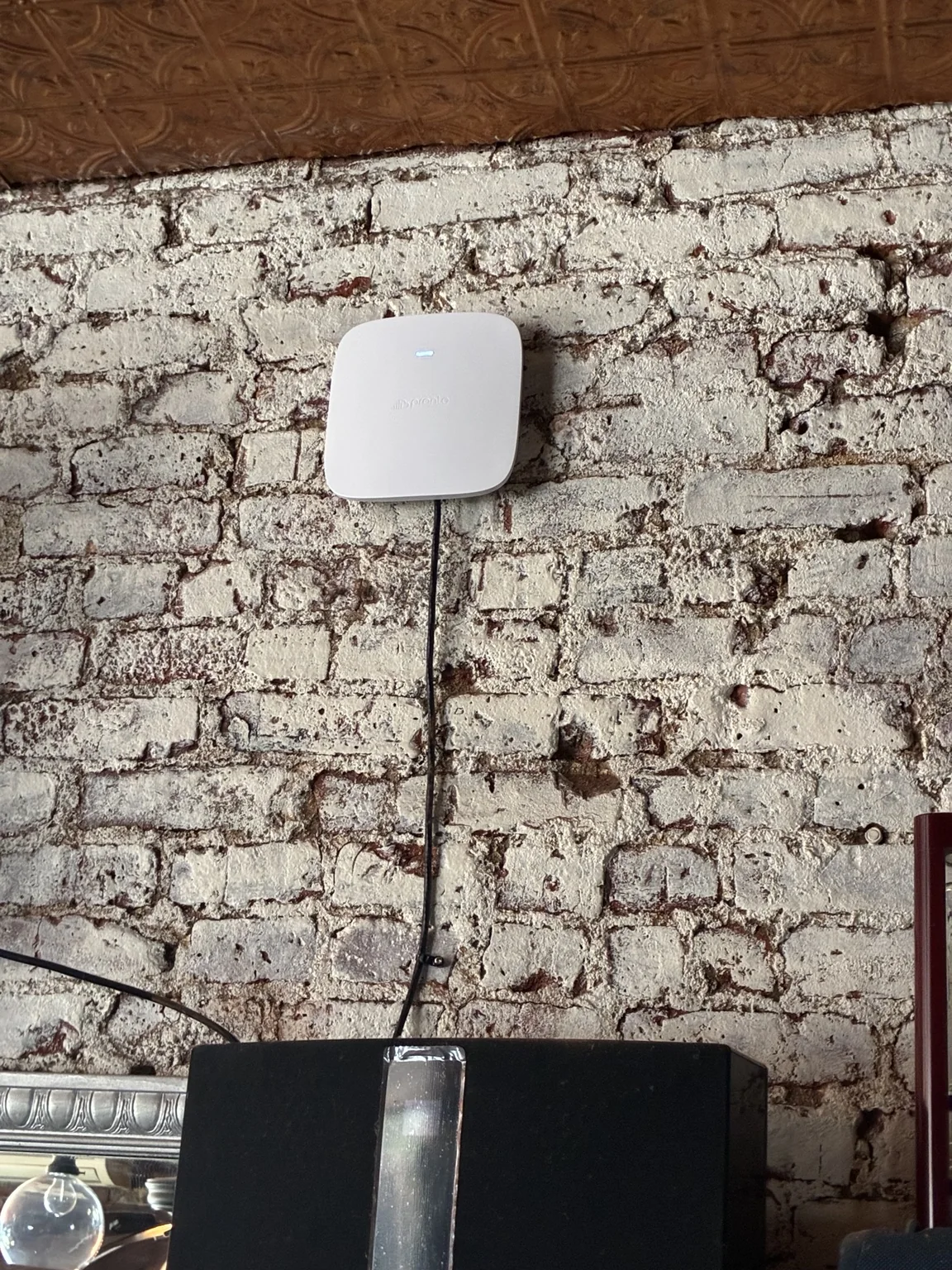 Wireless access point mounted on a brick wall at Mariella