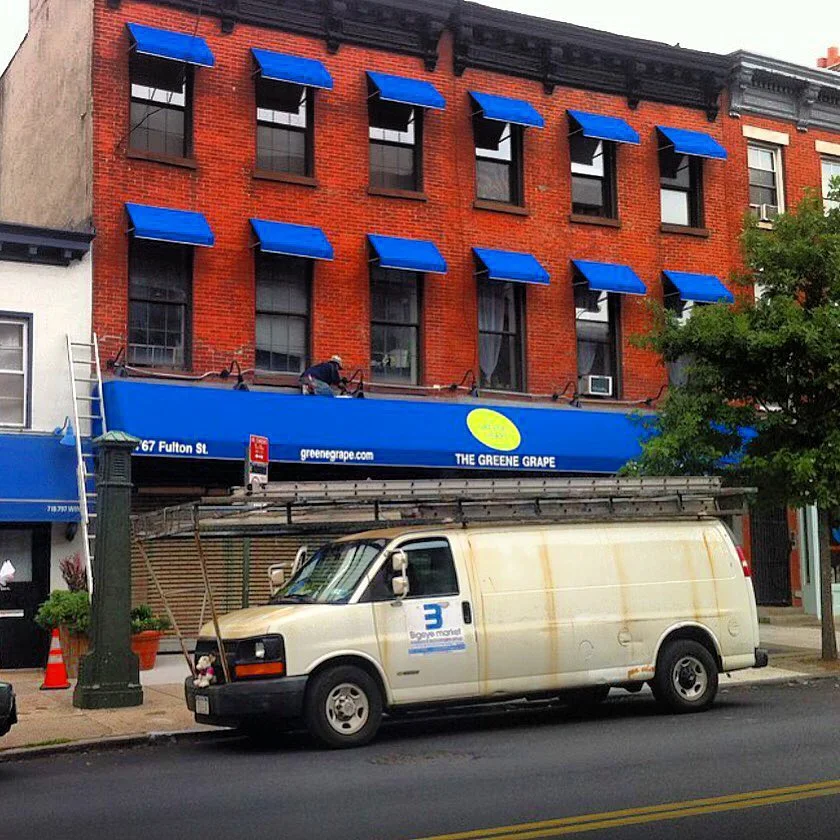 Blue awnings above the storefront on a corner building, Greene Grape