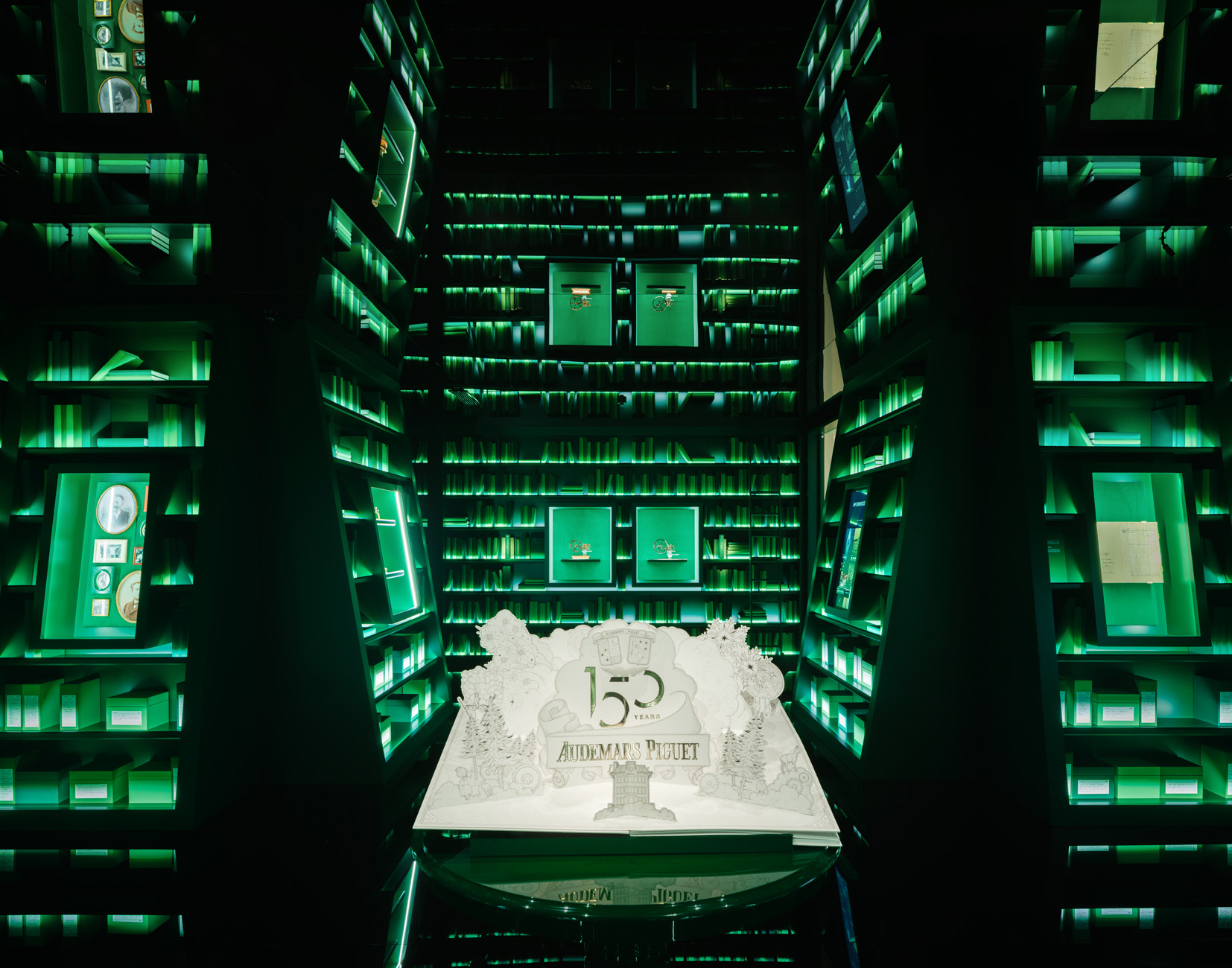 Green-lit display tower with a '150' sculpture at its base, Audemars Piguet 150 Years.