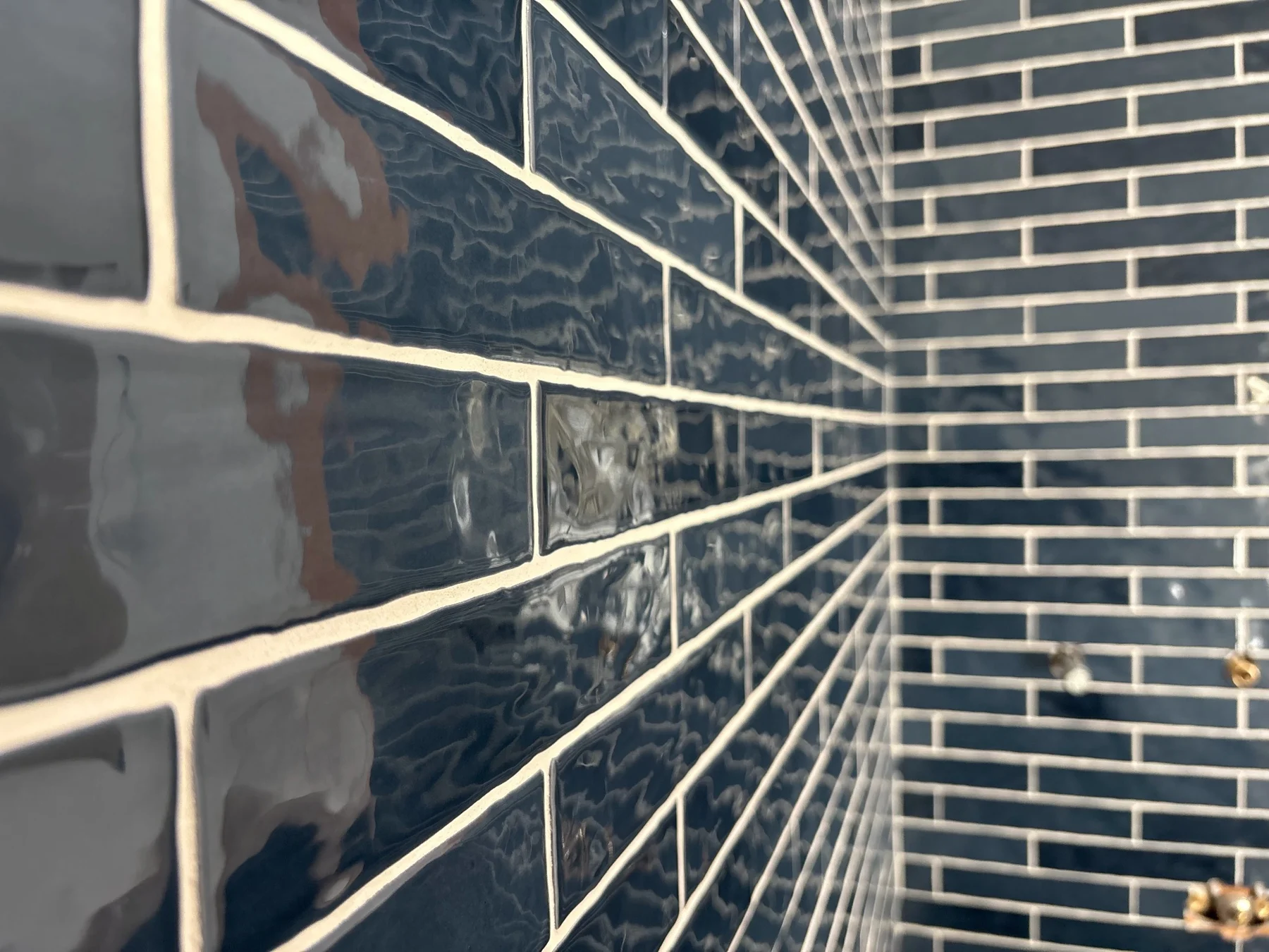 Blue ceramic subway tile — Glossy blue ceramic tile in an offset layout, with contrasting grout and coordinated inside corners.