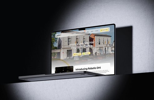 Laptop showing the homepage of a hair regrowth center website featuring a building image, headline 'World's Leading Hair Regrowth Centre,' and call-to-action buttons for booking appointments and live chat.