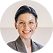 Smiling woman with dark hair pulled back, wearing a gray blazer and white top.