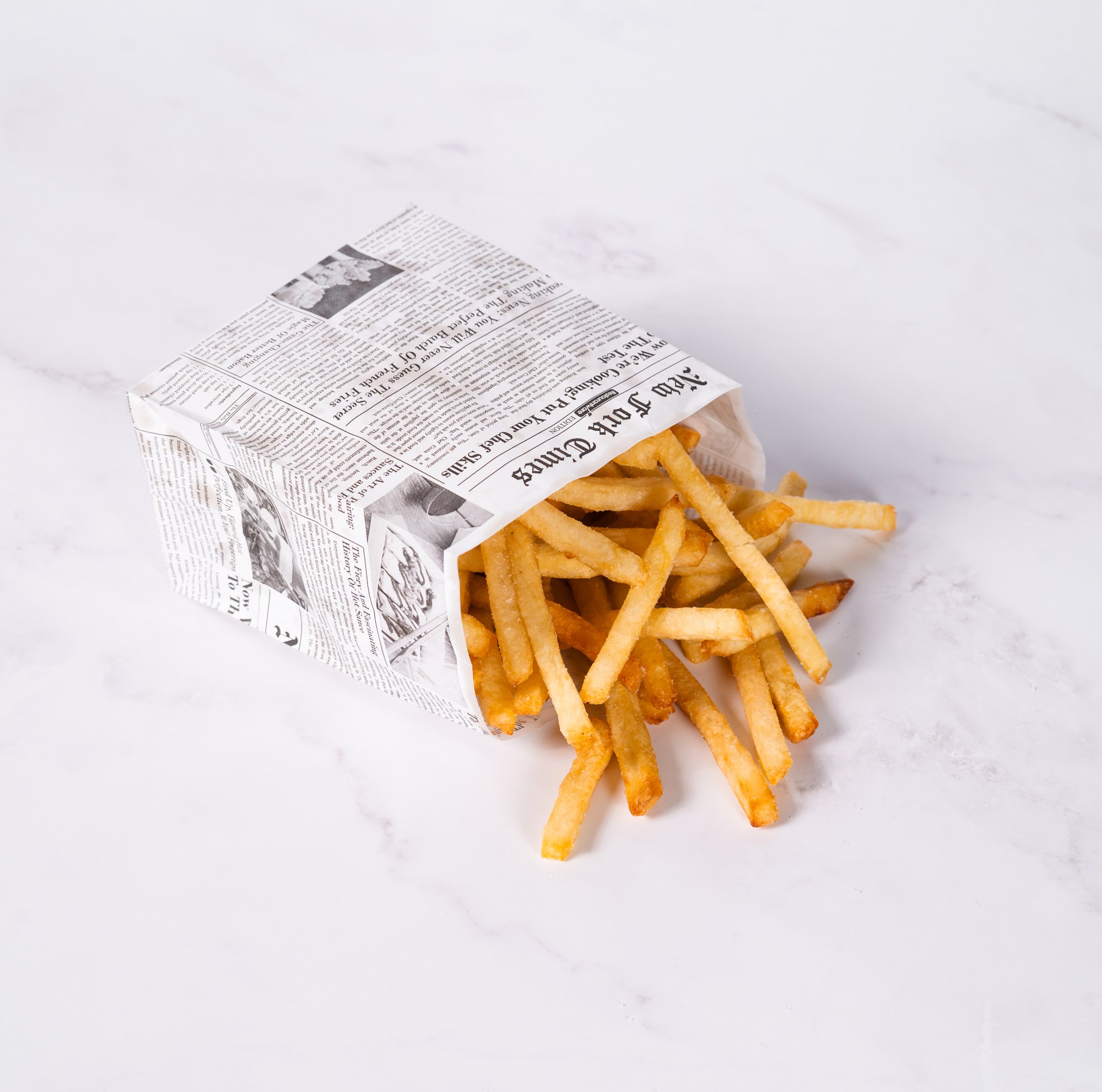 Hand-cut tallow fries spilling from a paper carton